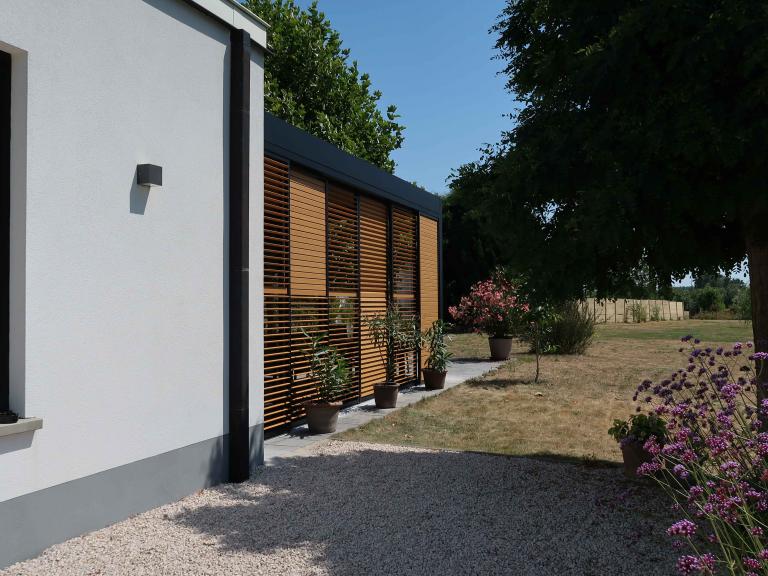 Demaeght Zonwering en interieur plaatste deze Renson Camargue terrasoverkapping aan restaurant La Barriga uit de Pinte. Een modern en strak design tegen een witte crepi gevel van Belgische kwaliteit. Houten schuifpanelen en een aluminium pergola.