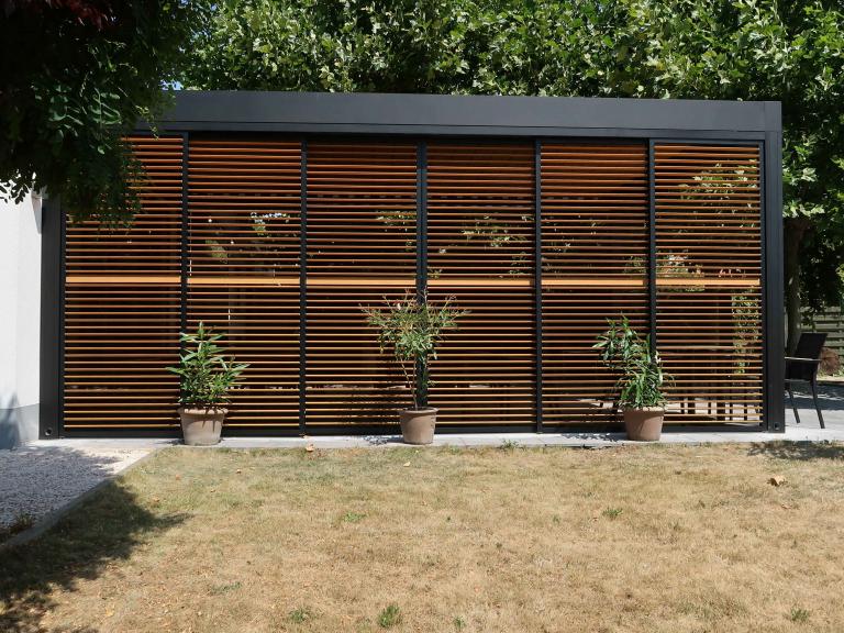 Demaeght Zonwering en interieur plaatste deze Renson Camargue terrasoverkapping aan restaurant La Barriga uit de Pinte. Een modern en strak design tegen een witte crepi gevel van Belgische kwaliteit. Houten schuifpanelen en een aluminium pergola.