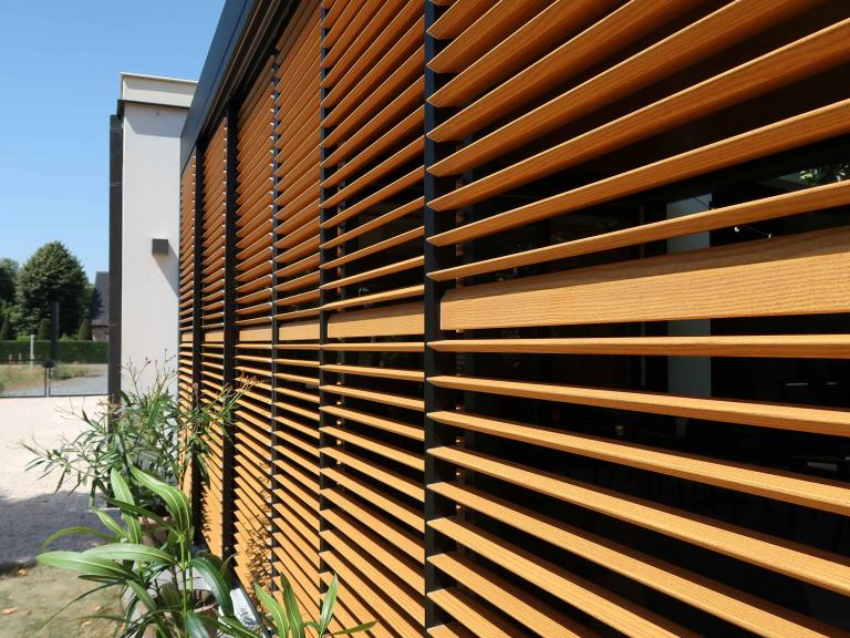 Demaeght Zonwering en interieur plaatste deze Renson Camargue terrasoverkapping aan restaurant La Barriga uit de Pinte. Een modern en strak design tegen een witte crepi gevel van Belgische kwaliteit. Houten schuifpanelen en een aluminium pergola.