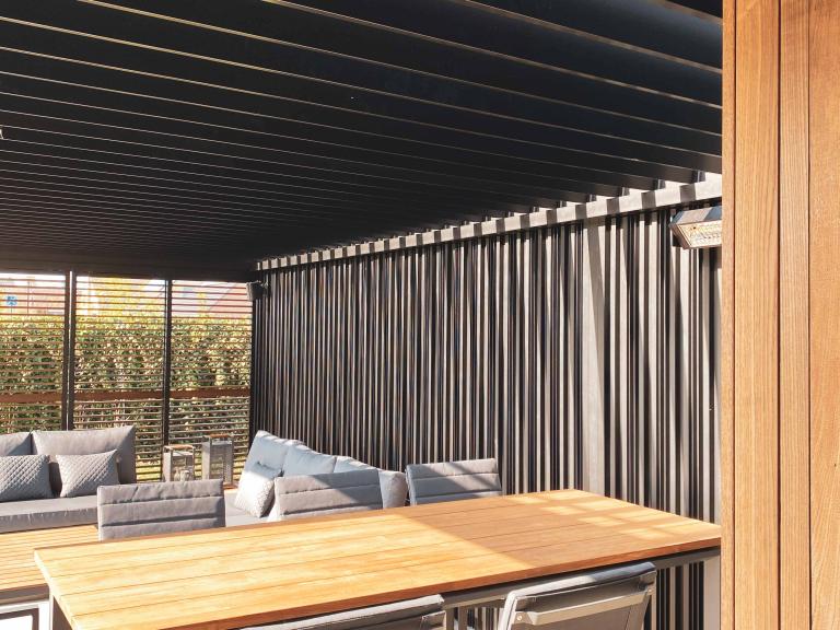 Renson Camargue terrasoverkapping met een houten bijgebouw van Carpentier geplaatst door Demaeght Zonwering & Interieur te Waregem. Met een aluminium lamellendak van Renson kan u het hele jaar door genieten. Architectuur terras design outdoor tuin zonwering zonnewering  