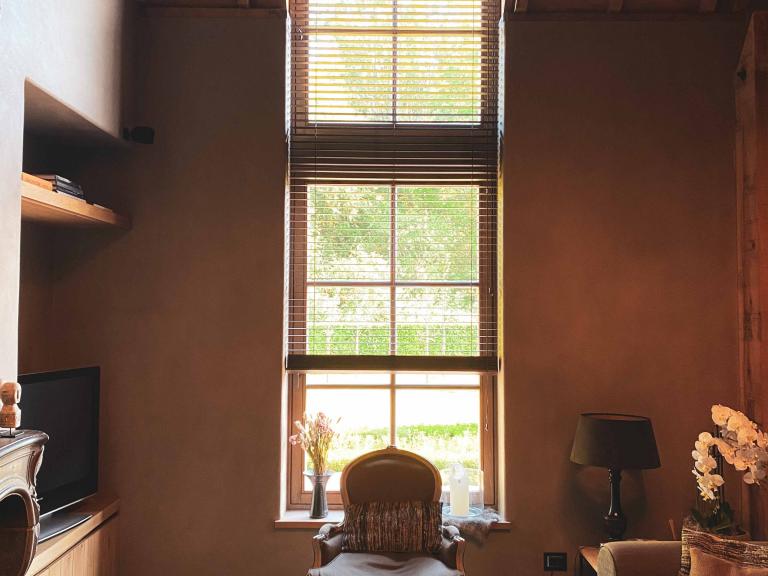 Demaeght zonwering en interieur plaatste deze houten lamellen aan dit groot raam in een landelijke woning te Deerlijk. 