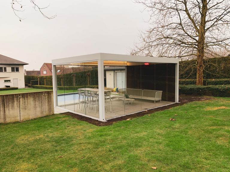 Renson Camargue terrasoverkapping geplaatst op deze mooie locatie te Anzegem als poolhouse aan een zwembad. Met zijn houten achterwand, glazen schuifwanden, led-verlichting en verwarming is dit een full Option lamellendak.