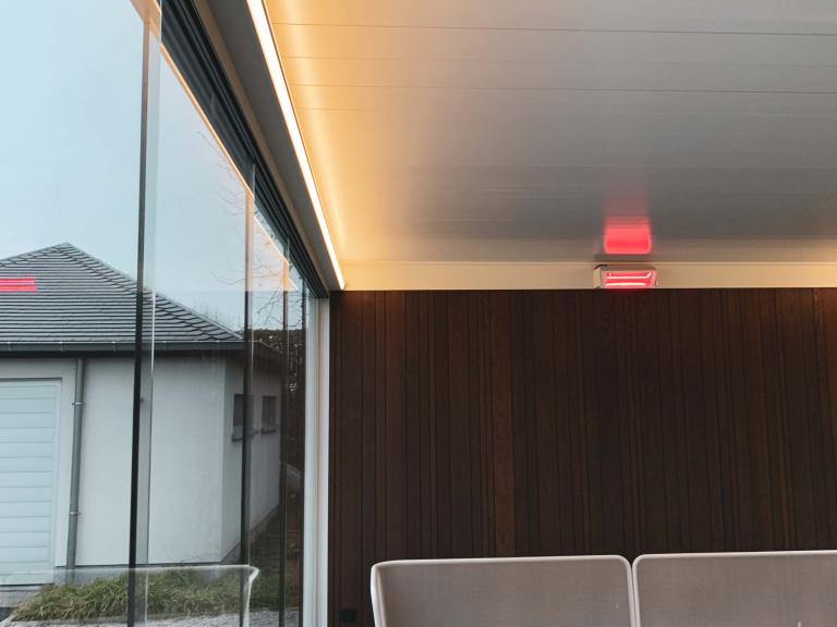 Renson Camargue terrasoverkapping geplaatst op deze mooie locatie te Anzegem als poolhouse aan een zwembad. Met zijn houten achterwand, glazen schuifwanden, led-verlichting en verwarming is dit een full Option lamellendak.