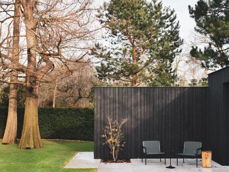 Demaeght Zonwering plaatste met Livinlodge aan deze tuinkamer schuifglas van Weinor te Mariakerke gent. Een mooi en strak design. De schuifpanelen schuiven in de wanden. Strak en modern design gecombineerd met belgische kwaliteit. Zwart hout. Tuinkamer en bureel volledig op maat in deze strakke tuin. architecturaal design 
